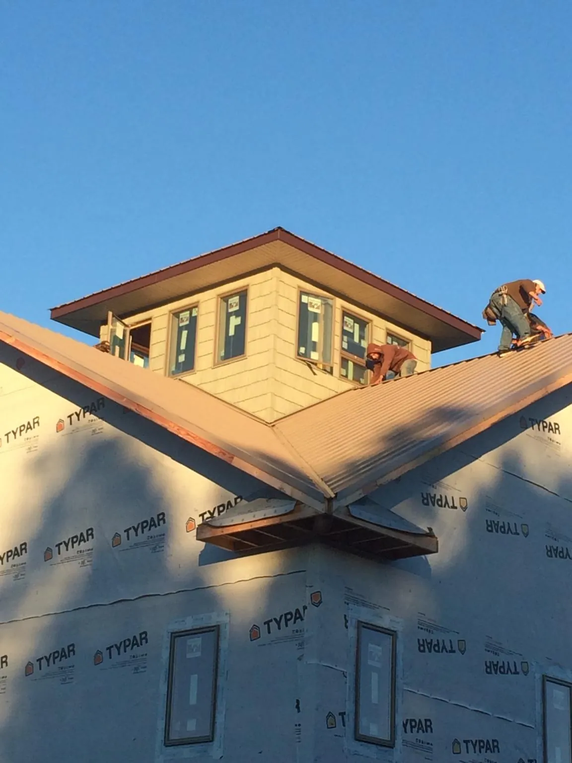 Roofers working around a rooftop cupola on a new metal roof at sunset — Roof Waterproofing in Andover by Roofing Brothers